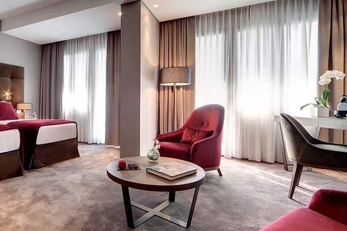 Una camera d'albergo con un letto grande, una scrivania, una sedia e un tavolino rotondo.