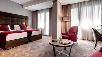 Una habitación de hotel con una cama grande, un escritorio, una silla y una mesa de centro redonda.