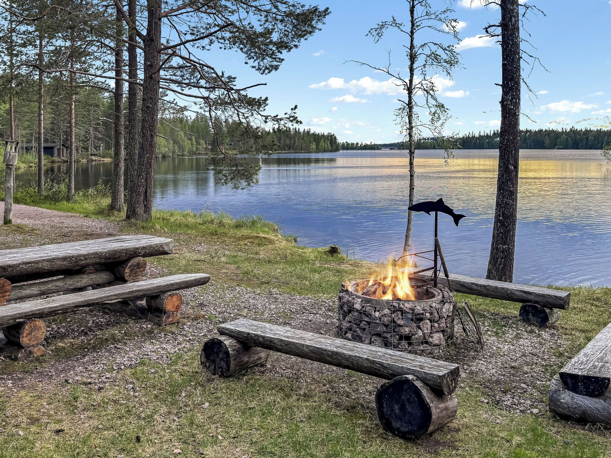 Leirintäalue järven rannalla, jossa on nuotiopaikka, piknikpöytiä ja näkymä järvelle.