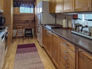 A compact kitchen with wooden cabinets, a built-in oven, a refrigerator, and a coffee machine.
