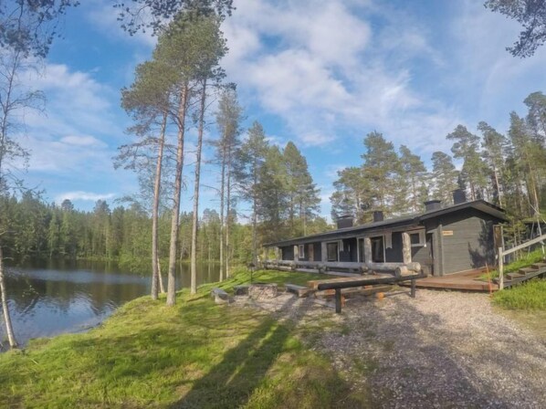 Escape to a serene forest retreat with a cabin-style accommodation surrounded by tranquil lake views and tall pine trees.