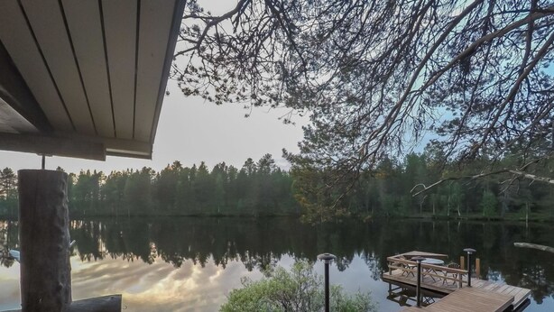 A wooden dock extending over a calm lake, surrounded by trees and a stone structure. - Sompsanniemi by Interhome (Kuusamo)