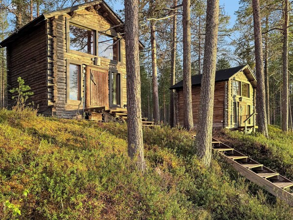 A log cabin with a wooden staircase leading to a deck.
