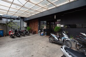 A covered parking area with several scooters and motorcycles parked. - RedDoorz Plus @ Kemayoran (Jakarta)