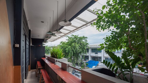 A balcony with a view of a cityscape, featuring a railing, benches, and potted plants. - RedDoorz Plus @ Kemayoran (Jakarta)