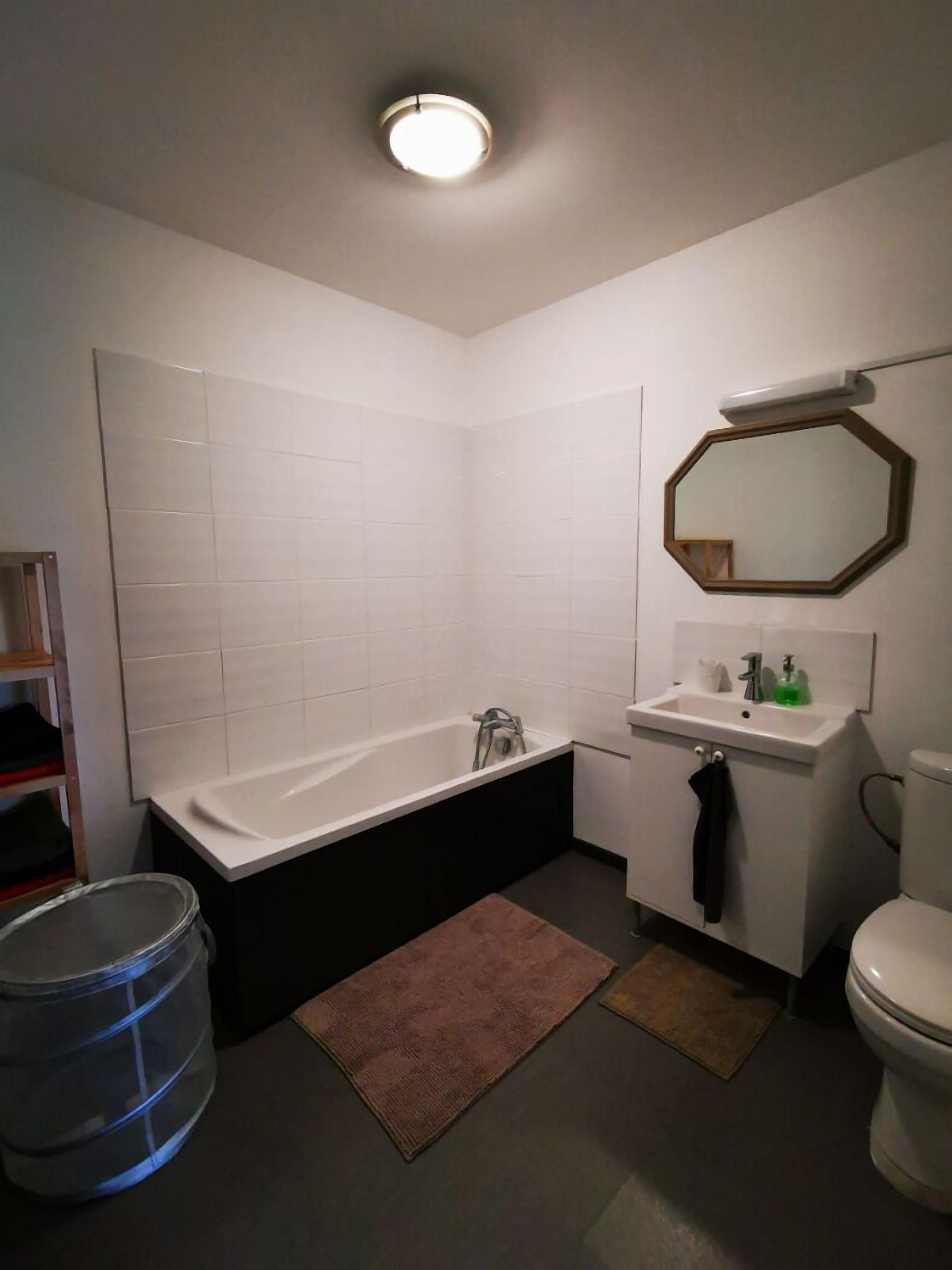 A bathroom with a bathtub, sink, toilet, and a mirror.