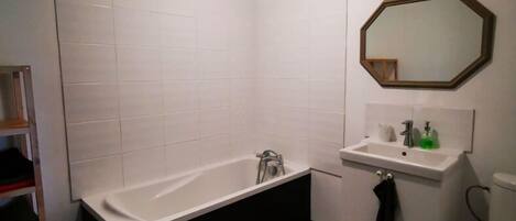 A bathroom with a bathtub, sink, toilet, and a mirror.