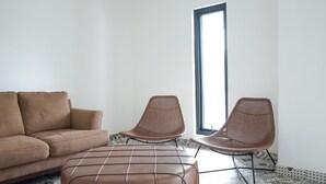 Ein Wohnzimmer mit einer Couch, zwei Korbstühlen und einem Couchtisch.