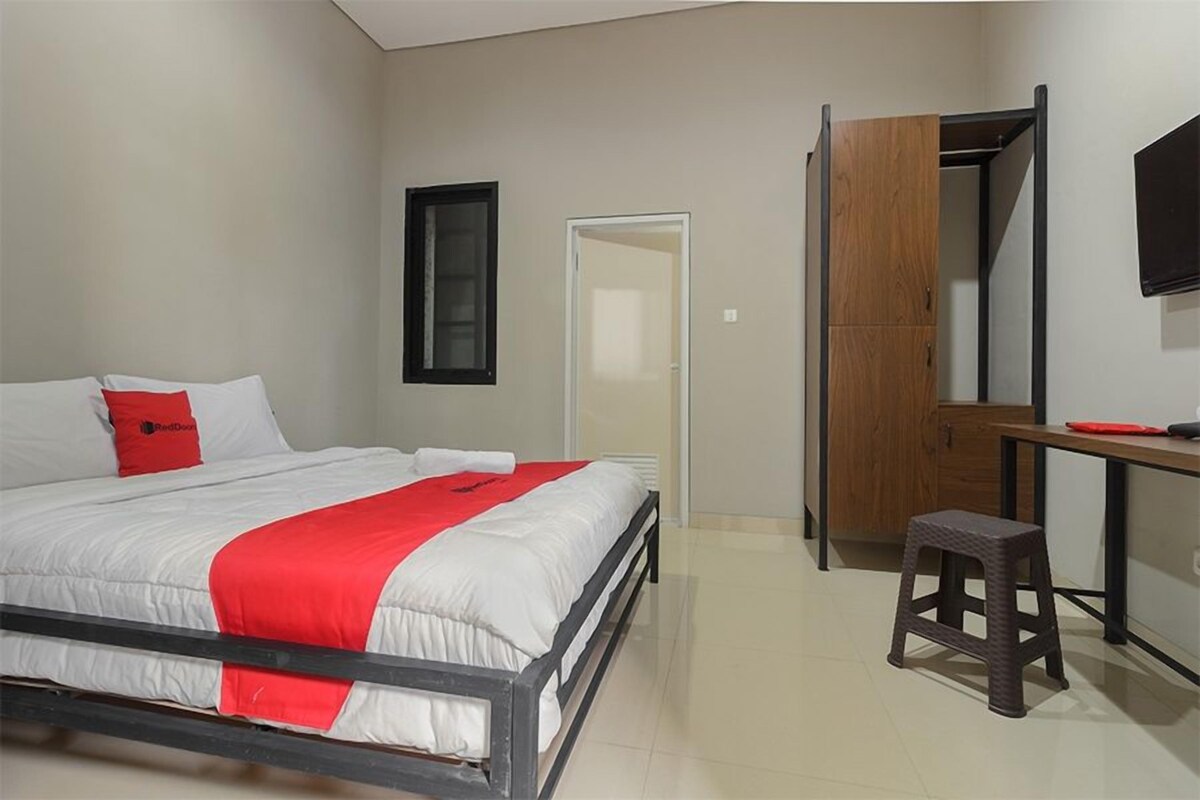 Une chambre à coucher comprenant un lit, un bureau, un tabouret, une armoire et un téléviseur.