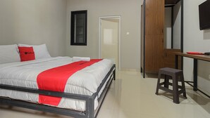 Ein Schlafzimmer mit Bett, Schreibtisch, Hocker, Kleiderschrank und Fernseher.