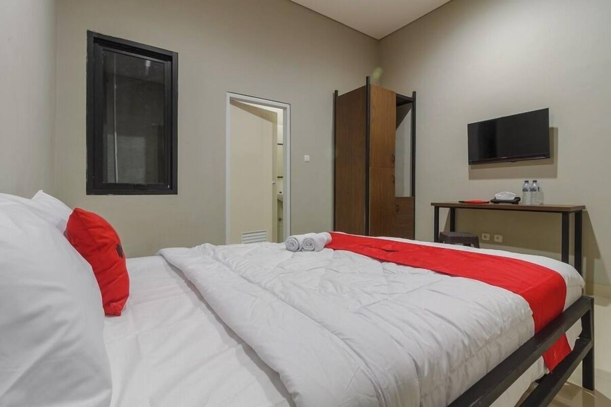 Ein Hotelzimmer mit Bett, Fernseher, Schreibtisch und Kleiderschrank.