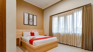 Een moderne hotelkamer met een groot bed, een houten hoofdeinde en een groot raam met gordijnen.