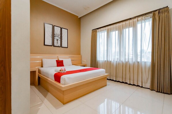 Een moderne hotelkamer met een groot bed, een houten hoofdeinde en een groot raam met gordijnen.