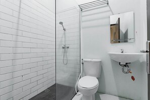 Een moderne badkamer met witte betegelde wanden, een douchecabine van glas, een wit toilet en een wastafel met een spiegel erboven.