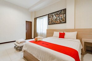 Hotelkamer met een groot bed, een houten hoofdbord, een schilderij aan de muur, een raam met gordijnen en een nachtkastje met een lamp.