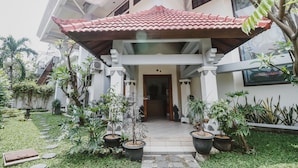 A building with a covered entrance, potted plants, and a well-maintained garden. - RedDoorz Syariah near Gelora Delta Sidoarjo (Sidoarjo)