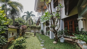 A courtyard with a pathway, potted plants, and a building with a balcony. - RedDoorz Syariah near Gelora Delta Sidoarjo (Sidoarjo)