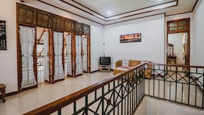 A spacious living area with a wooden railing, a television, and a sofa. - RedDoorz Syariah near Gelora Delta Sidoarjo (Sidoarjo)