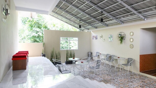 Amplio patio con techo alto, suelo de baldosas y una variedad de opciones de asiento, incluyendo sillas y un banco.