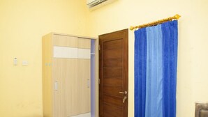 Ein Zimmer mit einem Holzschrank, einer geschlossenen Tür und einem blauen Vorhang.