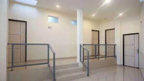 A clean, modern hallway with metal railings, a tiled floor, and doors labeled with numbers. - RedDoorz near Malioboro Mall 2 (Yogyakarta)