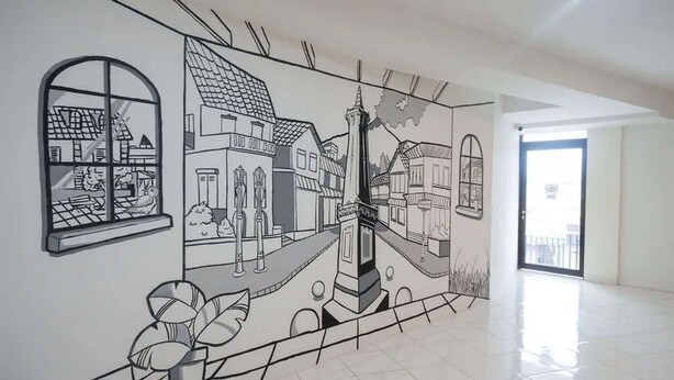 A hallway with a mural depicting a town scene, including buildings, a tower, and a street. - RedDoorz near Malioboro Mall 2 (Yogyakarta)