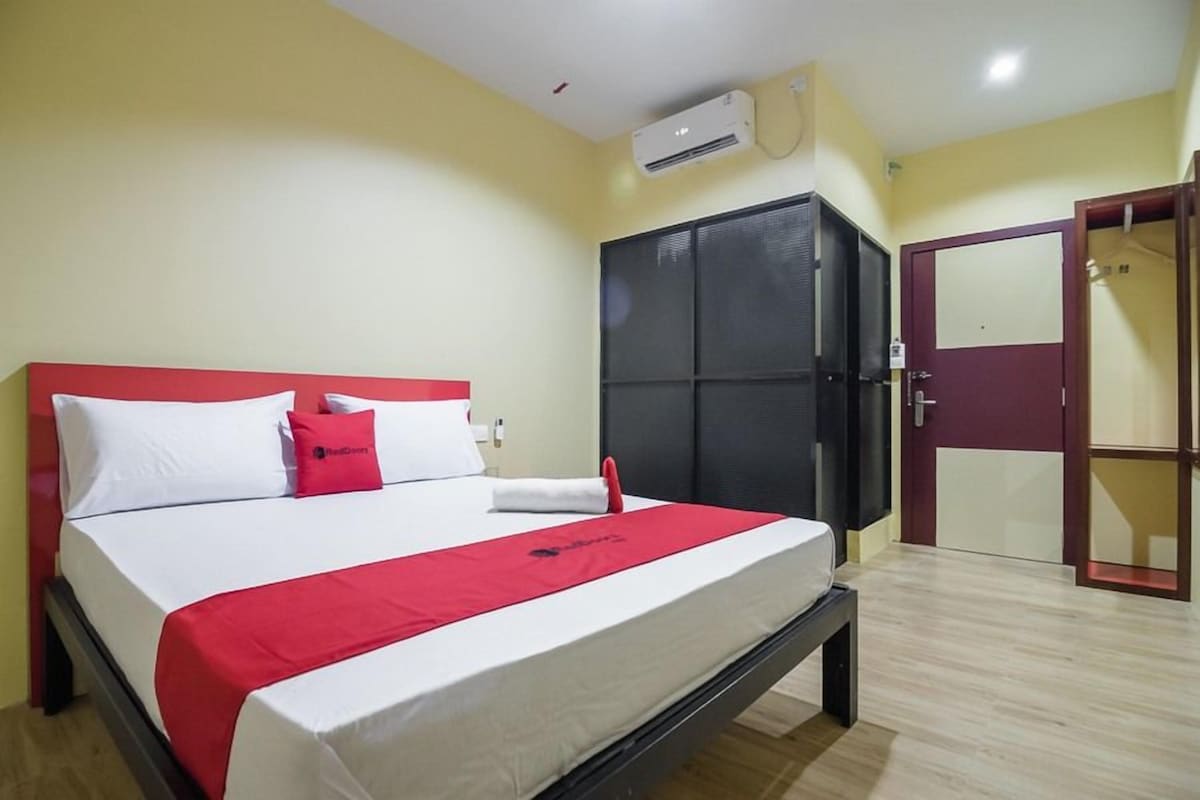 Quarto de hotel com uma cama, um guarda-roupa e uma porta.