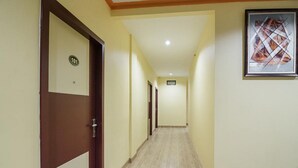 A hotel hallway with a wooden door labeled '101', a framed abstract artwork on the wall, and a tiled floor. - RedDoorz @ Batu Aji Batam 2 (Batam)