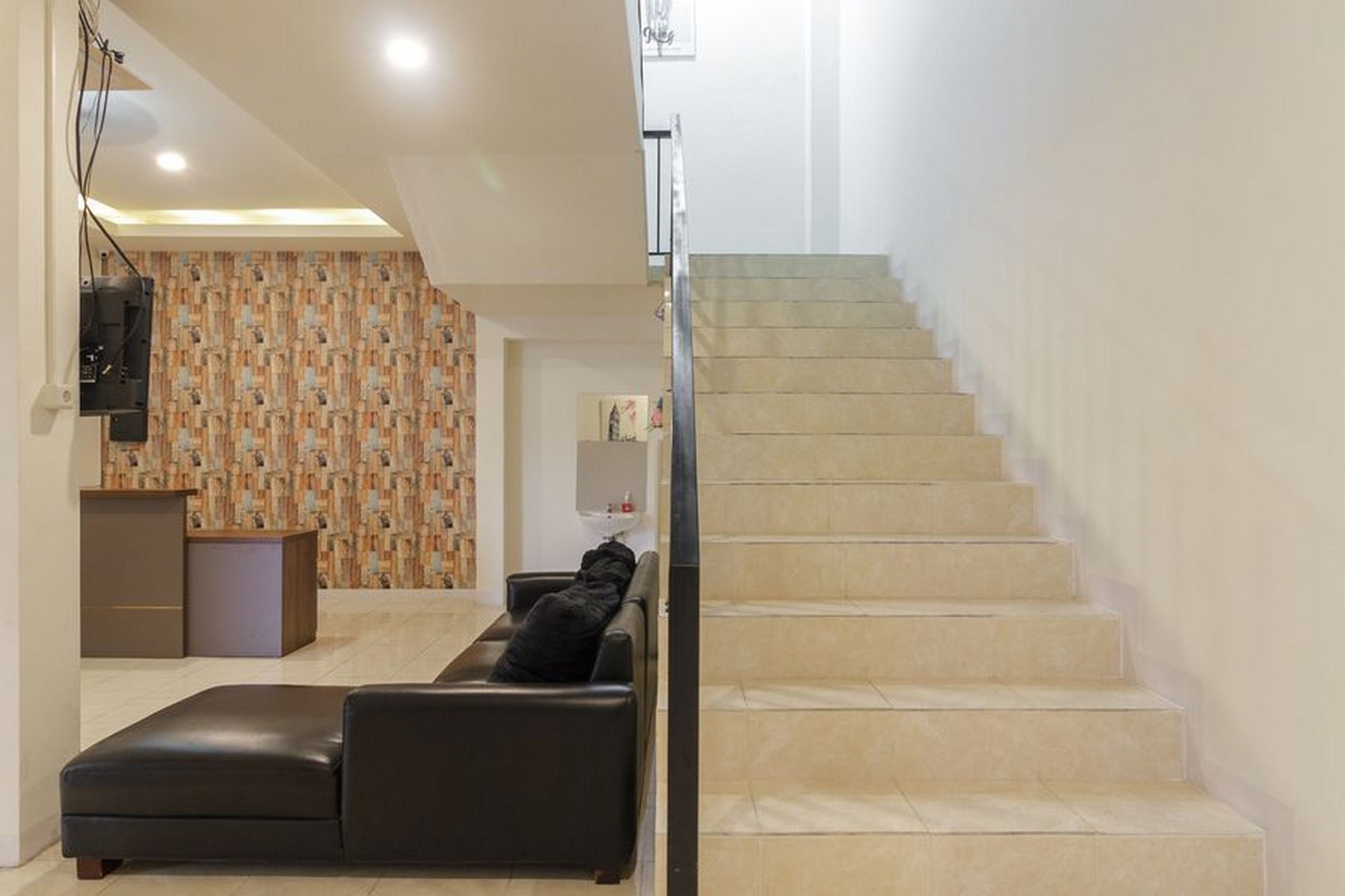 A modern interior with a staircase, a sofa, and a reception desk.