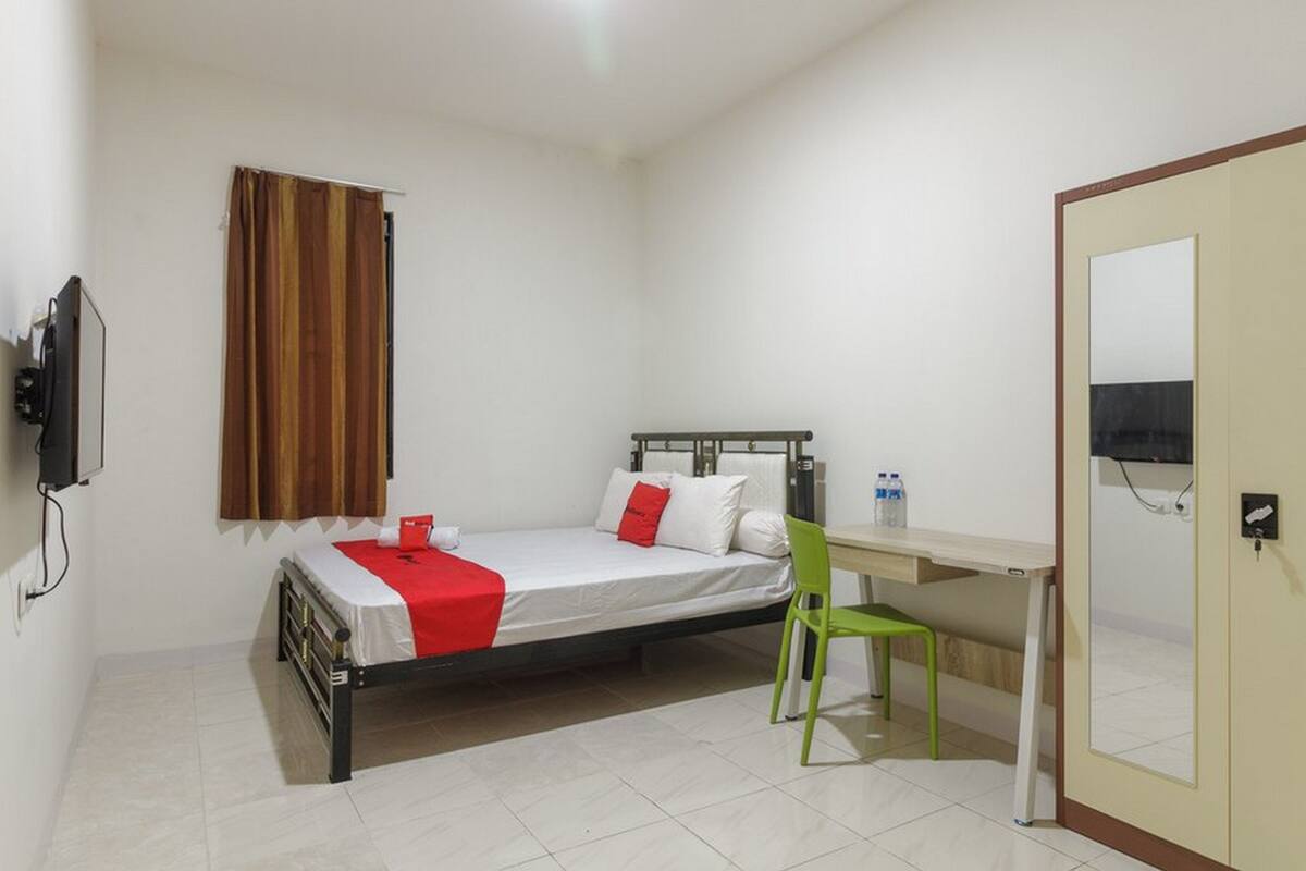 A bedroom with a bed, a desk, a chair, a television, and a wardrobe.