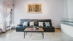 Un salon avec un canapé en cuir noir, une table basse et une œuvre d’art encadrée accrochée au mur.