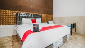 Une chambre d’hôtel avec un grand lit, une tête de lit ornée d’un motif géométrique et une couvre-lit rouge et blanche.
