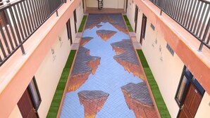 A corridor with a patterned floor, metal railings, and doors on either side. - RedDoorz near Terminal A Adisucipto Airport (Kalasan)