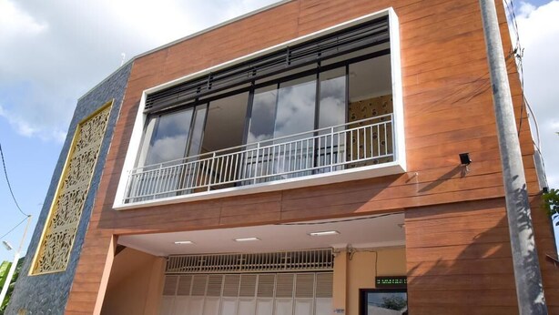 A modern building with a balcony, large windows, and a garage entrance. - RedDoorz near Terminal A Adisucipto Airport (Kalasan)