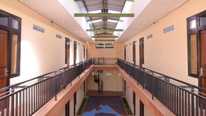 A corridor with a central staircase, metal railings, and a skylight. - RedDoorz near Terminal A Adisucipto Airport (Kalasan)