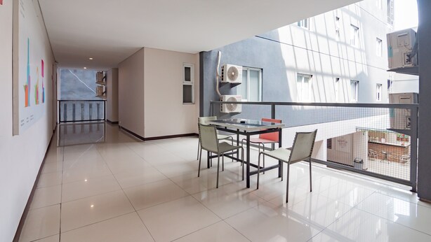 A modern apartment with a balcony, a dining area with a table and chairs, and a kitchen area visible through an open door. - RedDoorz Plus @ Dago Pojok 3 (Bandung)