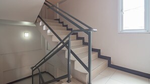 A modern staircase with metal railings and a mesh safety barrier, leading to a landing with a light fixture. - RedDoorz Plus @ Dago Pojok 3 (Bandung)