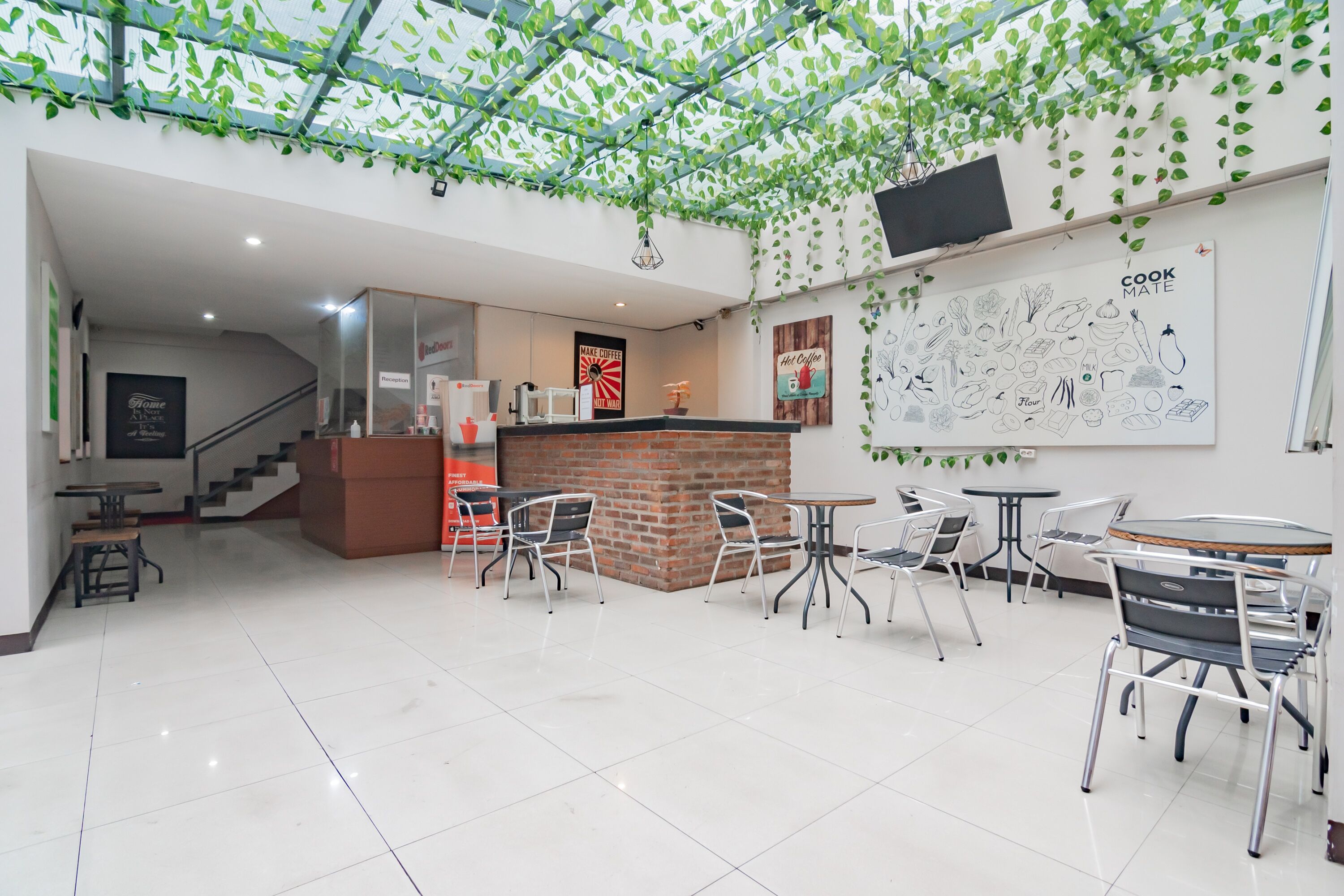 A cafe with a brick counter, white chairs, and a wall with a 'Cook Mate' sign.