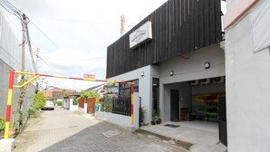 A gated entrance to a building with a metal gate, a paved driveway, and a small garden area with potted plants. - RedDoorz near Graha Saba UGM (Depok)