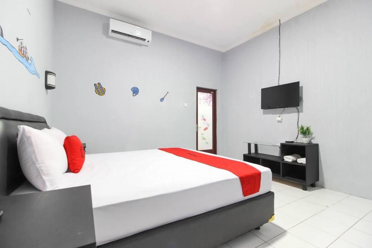 Quarto moderno com cama, televisão e escrivaninha.