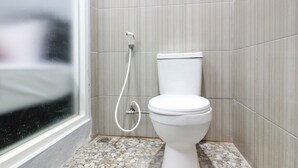 A bathroom with a toilet, a shower, and a tiled floor. - RedDoorz near Graha Saba UGM (Depok)