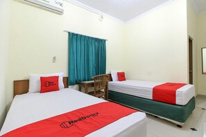 Deux lits simples avec une literie rouge et blanche, une chaise en bois, une petite table et un rideau de couleur turquoise.