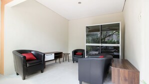 Una sala de estar moderna con un sofá, una silla, una mesita y un aparador.