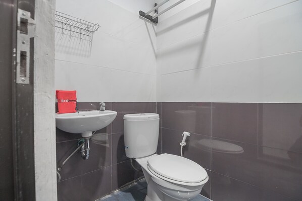 A bathroom with a white toilet, a sink, and a red cleaning product box.