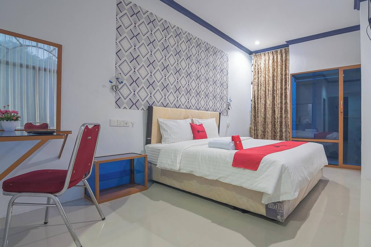 Habitación de hotel con cama, escritorio, silla, ventana y pared con diseño.