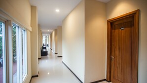 Un pasillo con una puerta de madera con la etiqueta 206, piso de baldosas y vista a un área de cocina a lo lejos.