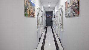 A hallway with white walls, black and white tiled floor, and doors on both sides. - RedDoorz Plus near Politeknik Negeri Malang (Malang)