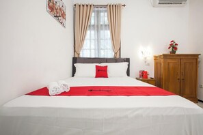Une chambre d’hôtel avec un lit, une table de chevet, une armoire en bois et une fenêtre avec des rideaux.