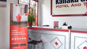 Uma área de recepção de hotel com uma placa RedDoorz, uma placa Kanaka Giri Hotel e uma placa 'ABERTO' no balcão.