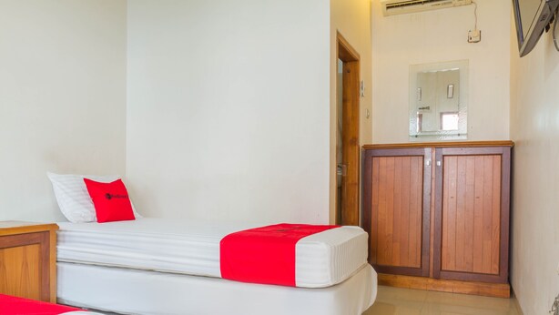 Un dormitorio con una cama, un armario de madera y un espejo en la pared.